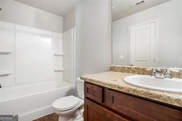 a bathroom with a granite countertop sink a toilet and bathtub