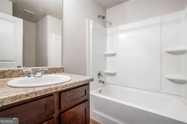a bathroom with a granite countertop tub sink and mirror