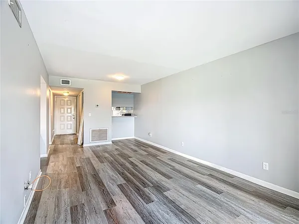 a view of kitchen and empty room with wooden floor