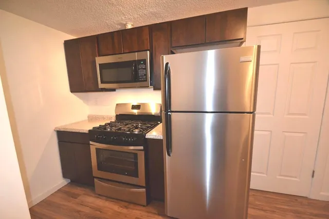a kitchen with stainless steel appliances granite countertop a refrigerator and a stove top oven