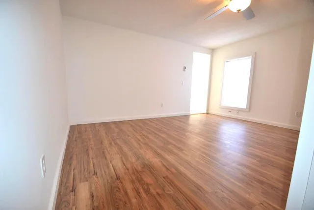 a view of an empty room with wooden floor and a window