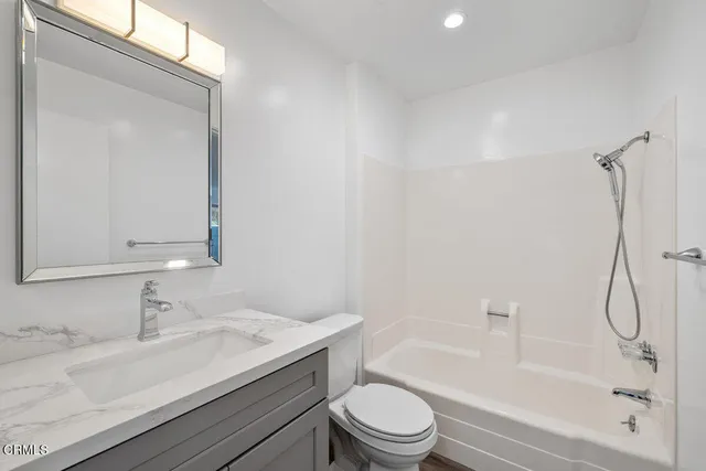 a bathroom with a granite countertop sink toilet and shower