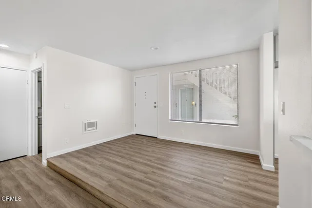 a view of an empty room with wooden floor and a window