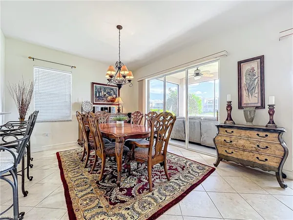 a view of a dining room and livingroom with furniture wooden floor a rug a painting and a chandelier