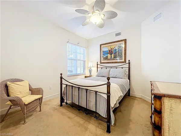 a bed sitting in a bedroom next to a window and a chandelier
