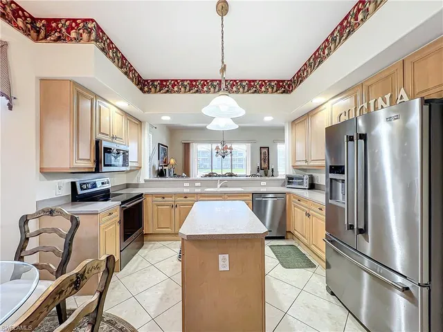 a kitchen with stainless steel appliances granite countertop a refrigerator a sink dishwasher a stove and white cabinets with wooden floor