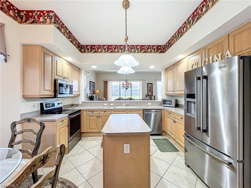 722 Regency Reserve Circle, Unit 3001 Naples, FL 34119 - Photo 8 of 50 a kitchen with stainless steel appliances granite countertop a refrigerator a sink dishwasher a stove and white cabinets with wooden floor
