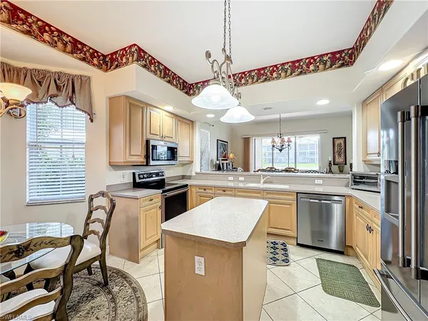 a kitchen with stainless steel appliances granite countertop a stove top oven a sink dishwasher a dining table and chairs with wooden floor