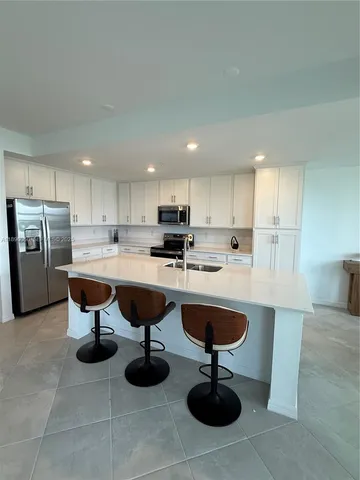 a kitchen with refrigerator and chairs