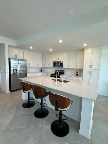 a kitchen with stainless steel appliances granite countertop a sink and a refrigerator