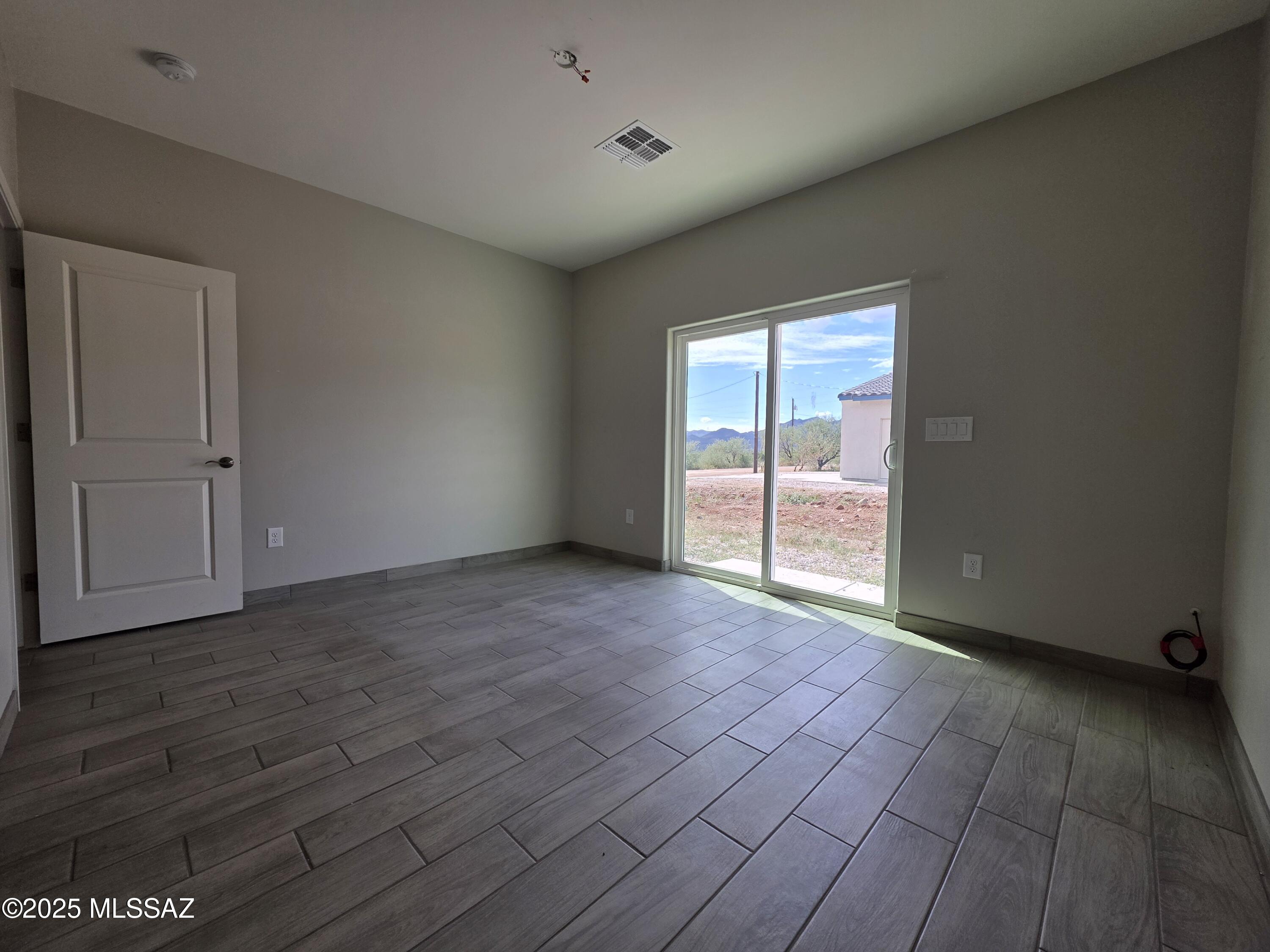 120 Via Venezuela Rio Rico, AZ 85648 - Photo 18 of 37 a view of an empty room with wooden floor and a window