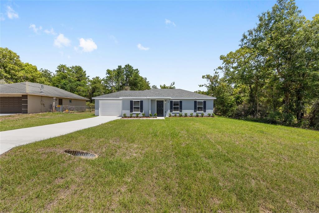 29 Olive Cir Loop Ocala, FL 34472 - Photo 3 of 49 a front view of house with yard and trees in the background