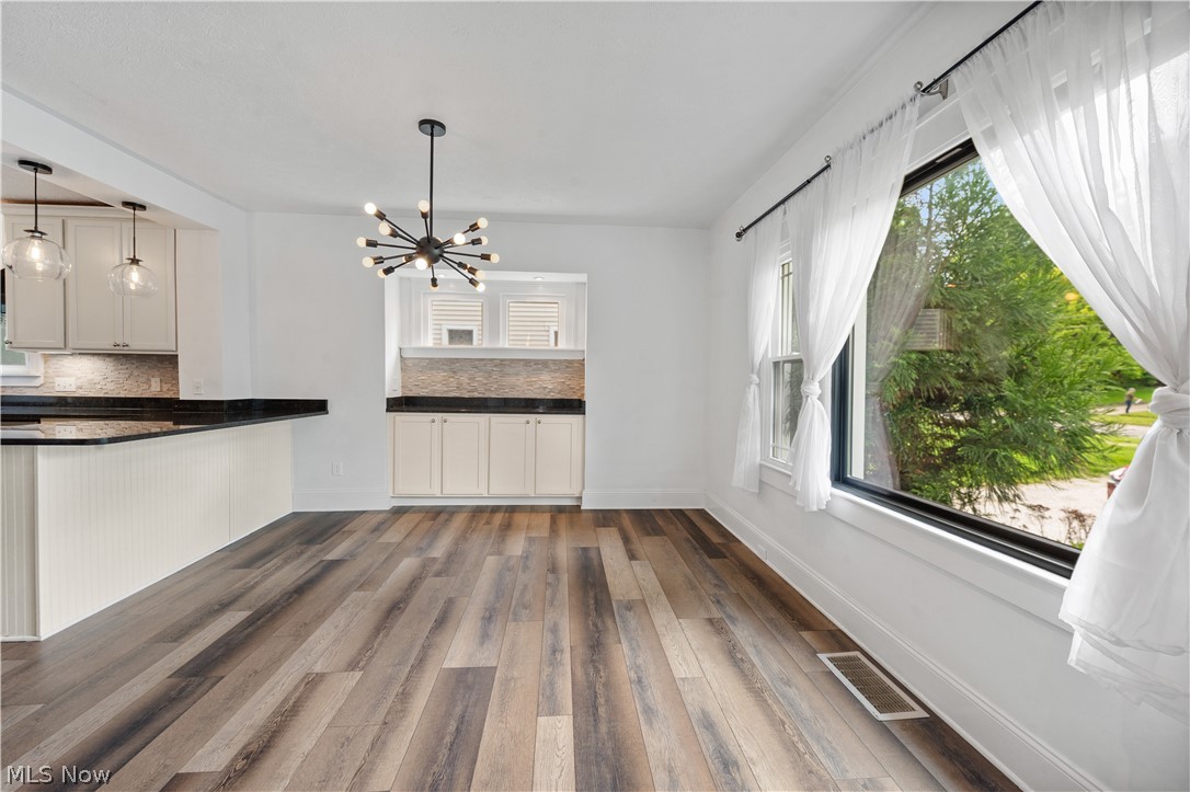 371 Merriman Road Akron, OH 44303 - Photo 7 of 27 Spacious room featuring wide wood-finish flooring, a contemporary sputnik chandelier, and a large window