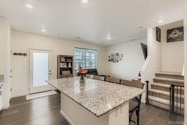 a kitchen with stainless steel appliances granite countertop a sink dishwasher and a refrigerator with wooden floor