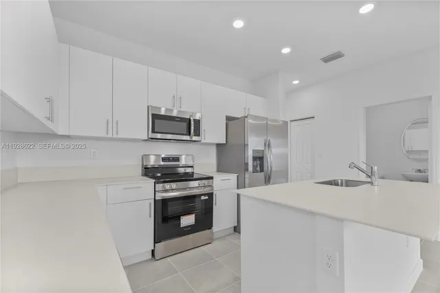 a kitchen with stainless steel appliances granite countertop a stove a sink and a refrigerator