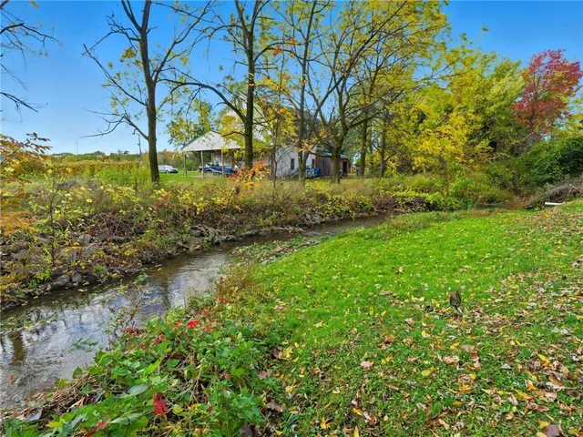 a backyard of a house with lots of green space and fountain in the back