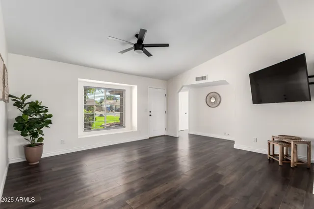 a view of a livingroom with a flat screen tv potted plant and a ceiling fan