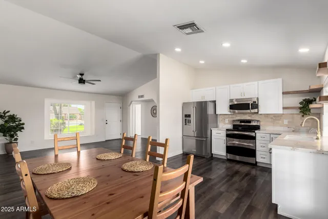 a kitchen with stainless steel appliances granite countertop a stove top oven a refrigerator a sink and a dining table with wooden floor