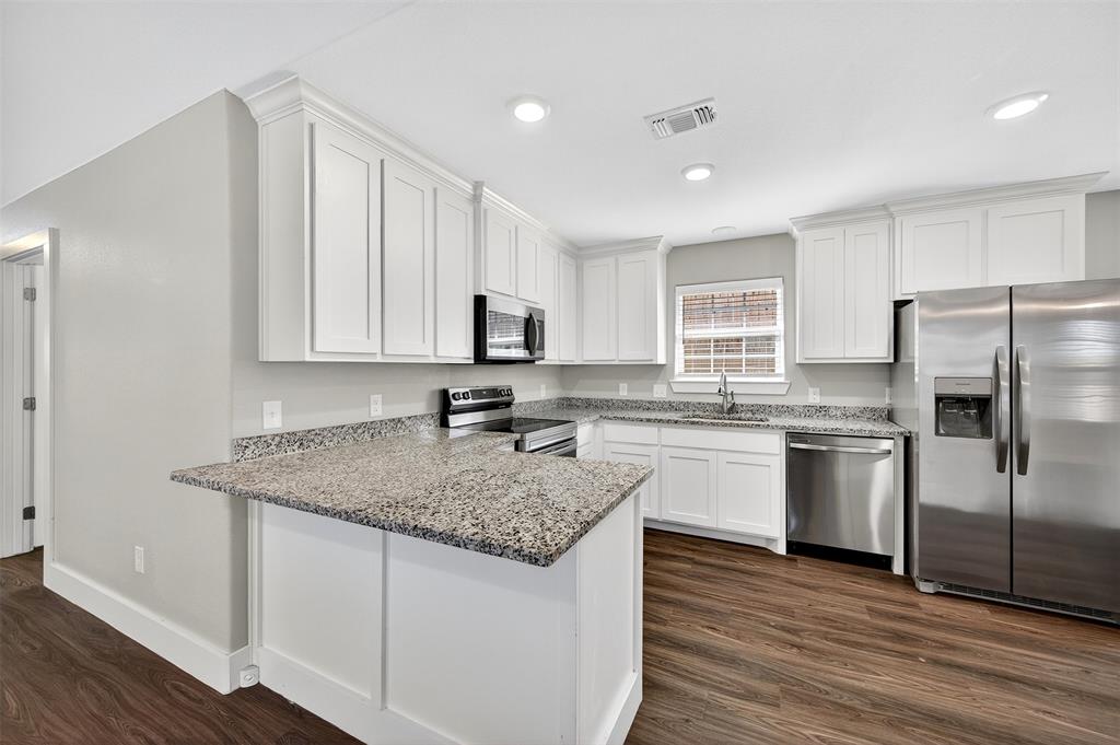 1016 Ray Drive Denison, TX 75020 - Photo 5 of 7 a kitchen with stainless steel appliances granite countertop a sink dishwasher a refrigerator and white cabinets with wooden floor