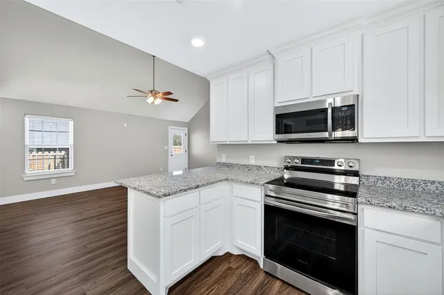 a kitchen with stainless steel appliances granite countertop a stove microwave and cabinets