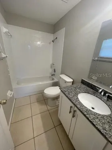 a bathroom with a granite countertop sink a toilet and shower