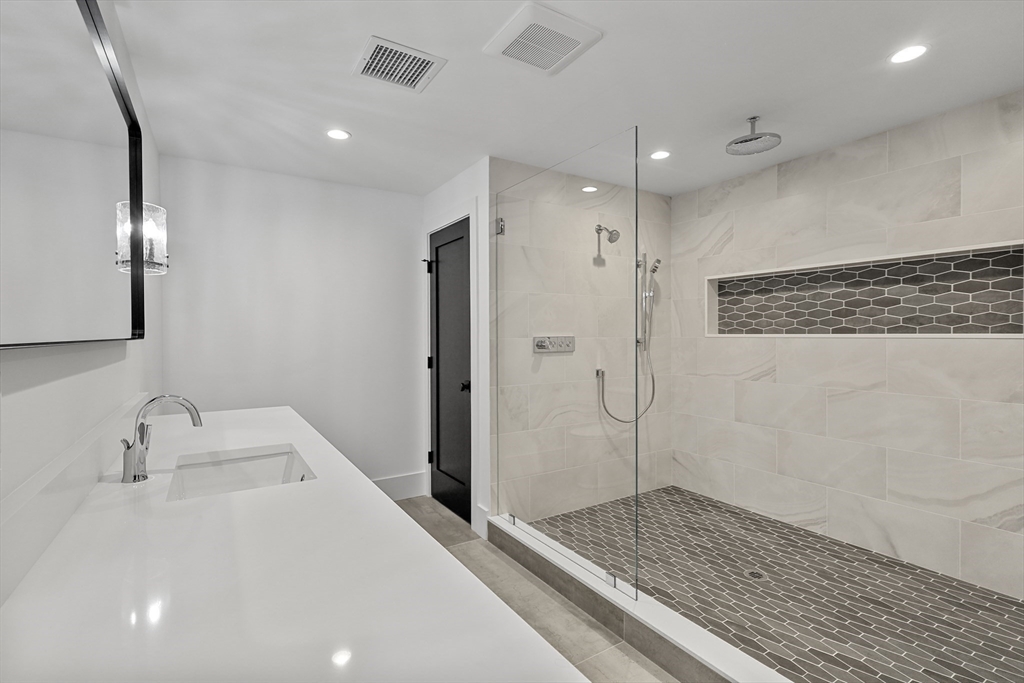 23 Dwight Road Needham, MA 02492 - Photo 35 of 40 a bathroom with a shower sink and mirror