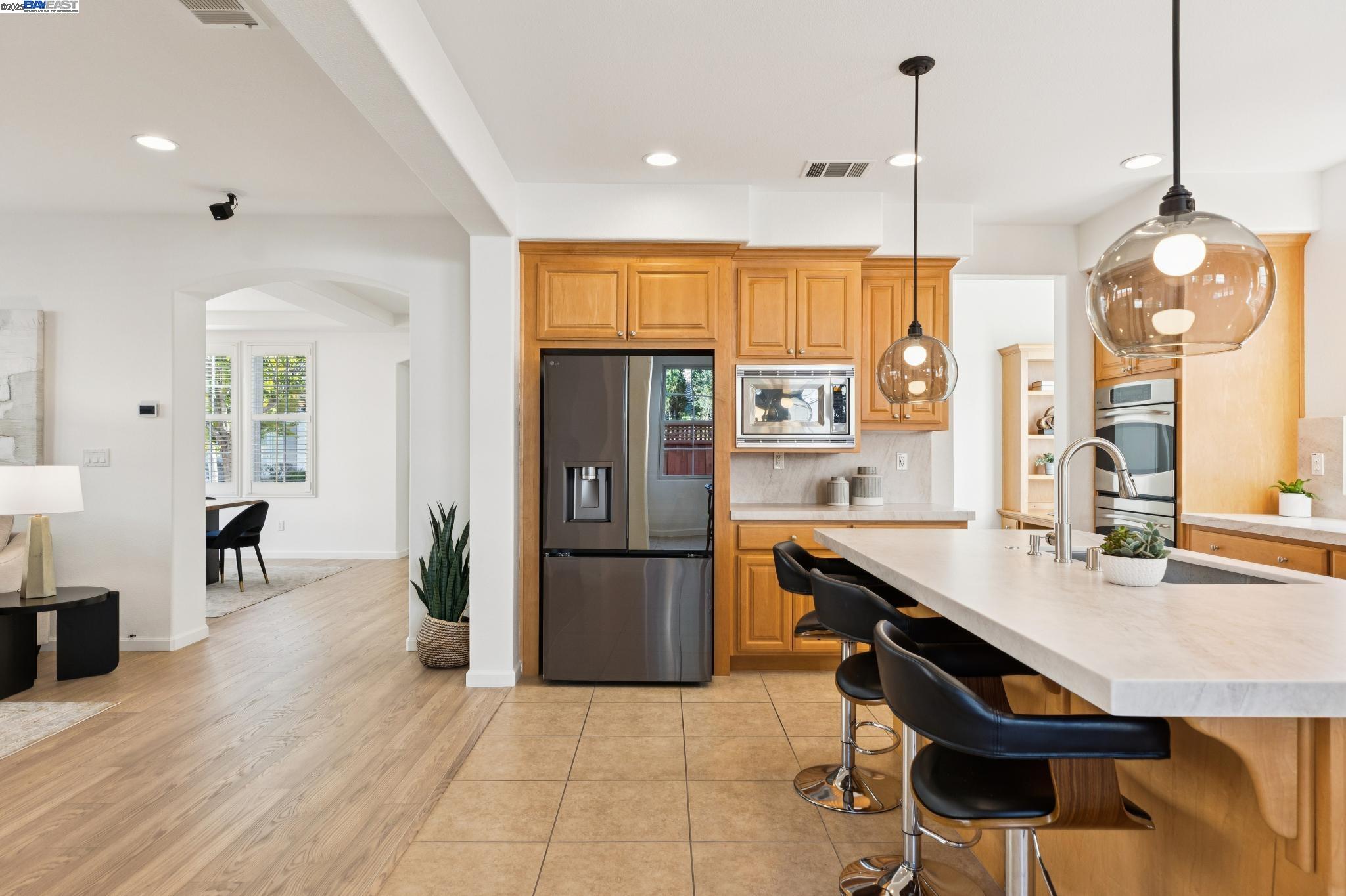 5 Cornelius Square Alameda, CA 94501 - Photo 17 of 60 a kitchen with stainless steel appliances granite countertop a refrigerator a sink dishwasher a stove and a dining table with wooden floor