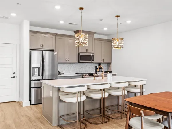 a kitchen with stainless steel appliances a table chairs refrigerator and microwave