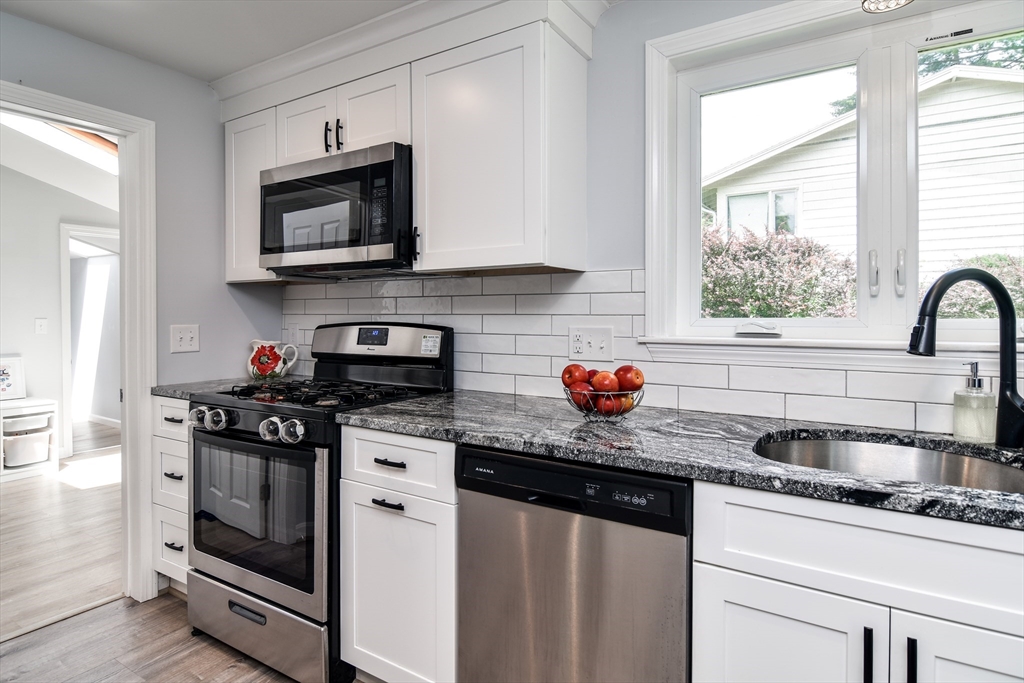 10 Ruth Drive Framingham, MA 01701 - Photo 12 of 28 a kitchen with stainless steel appliances granite countertop a sink stove a microwave and cabinets