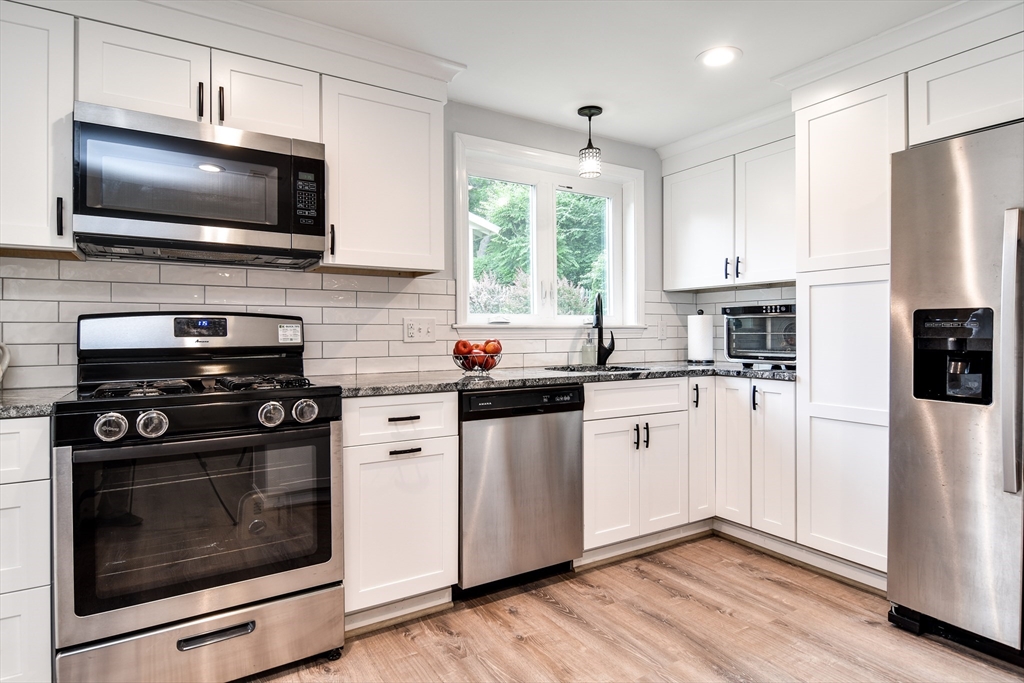 10 Ruth Drive Framingham, MA 01701 - Photo 10 of 28 a kitchen with stainless steel appliances a stove a microwave and white cabinets