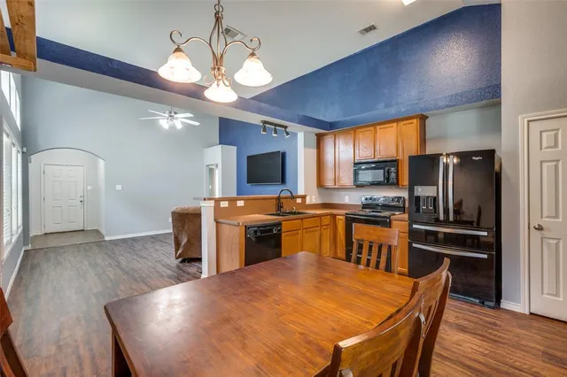 a kitchen with stainless steel appliances a dining table chairs stove refrigerator and microwave