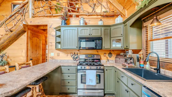 a kitchen filled with stainless steel appliances kitchen island granite countertop a refrigerator a sink and wooden cabinets