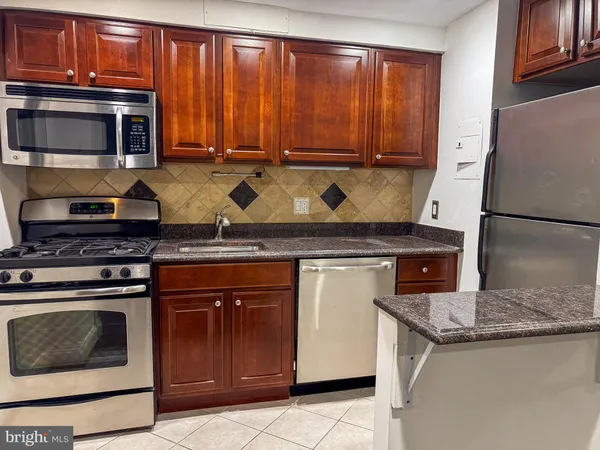 a kitchen with granite countertop a stove top oven microwave and cabinets
