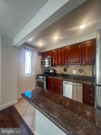 a kitchen with granite countertop wooden cabinets a stove a sink and dishwasher