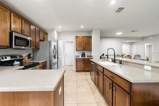 a kitchen with stainless steel appliances a sink a stove a refrigerator cabinets and a counter top space