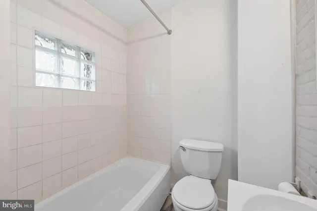 a white toilet sitting next to a bath tub
