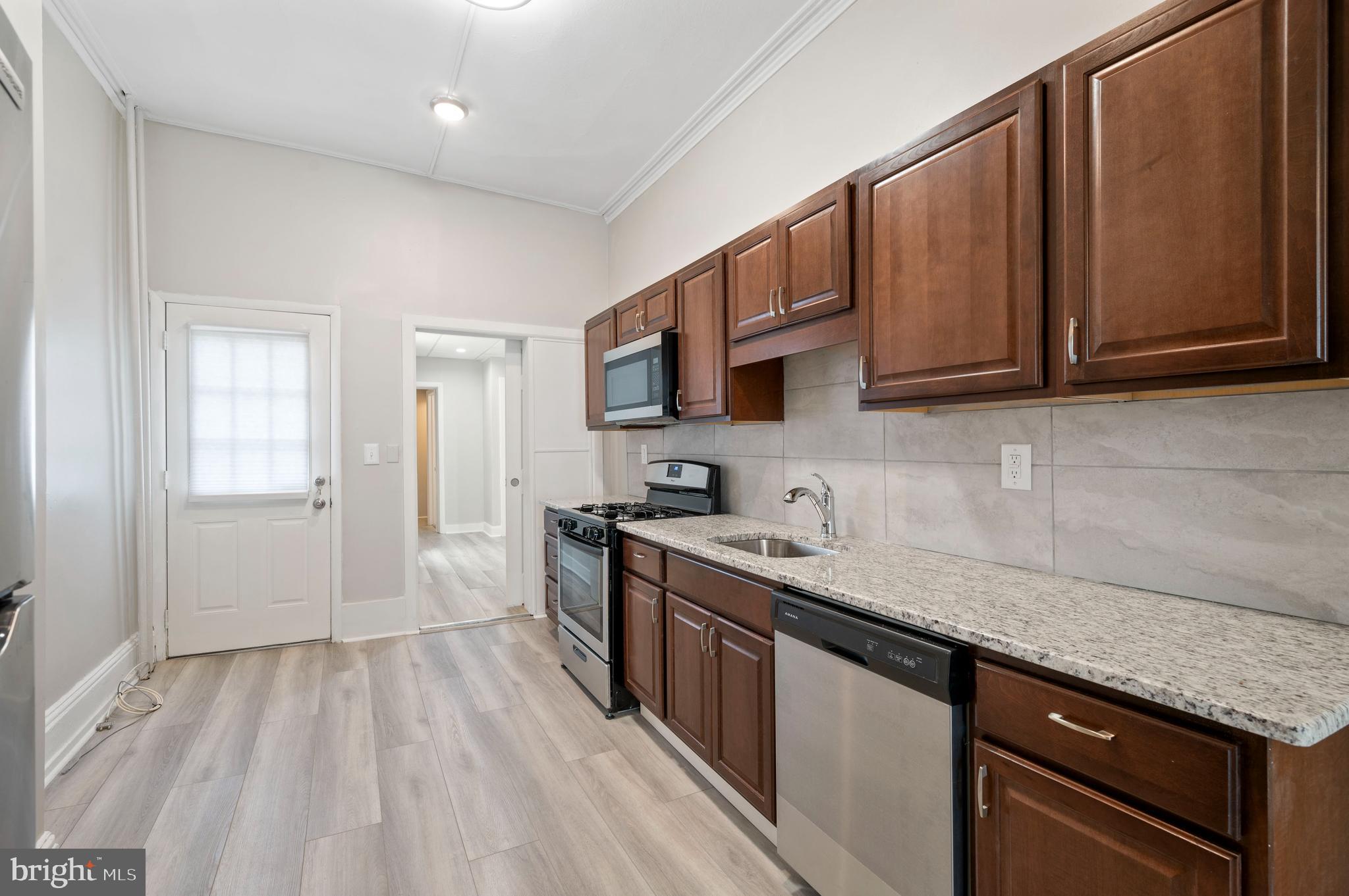 2304 Catharine Street, Unit 1 Philadelphia, PA 19146 - Photo 6 of 14 a kitchen with stainless steel appliances granite countertop a sink stove and microwave