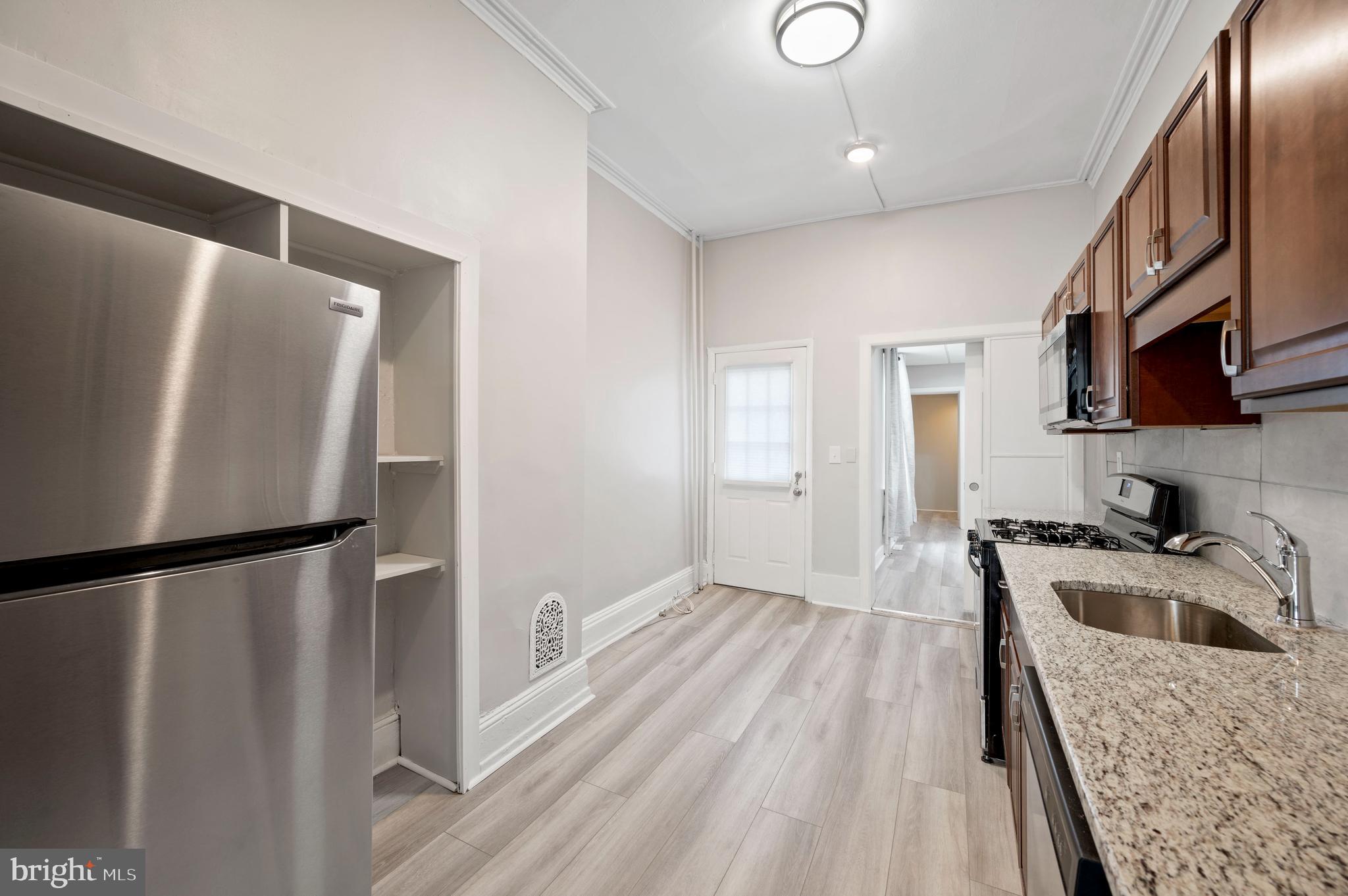 2304 Catharine Street, Unit 1 Philadelphia, PA 19146 - Photo 7 of 14 a kitchen with granite countertop a refrigerator a sink a stove and cabinets