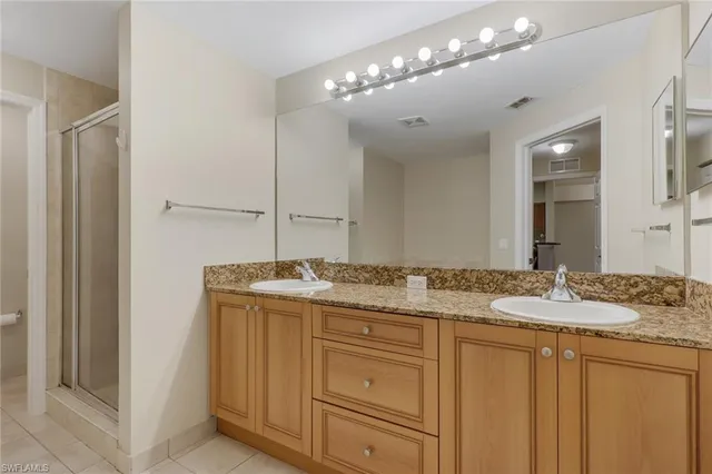 a bathroom with a granite countertop sink a mirror and a shower