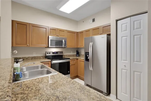 a kitchen with granite countertop a refrigerator stove and microwave
