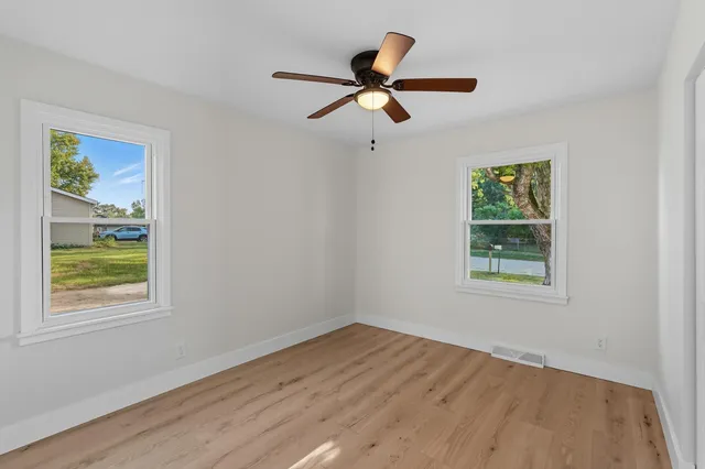 a view of empty room with wooden floor and window