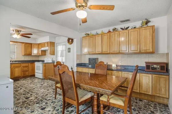 a dining room with stainless steel appliances kitchen island granite countertop a table chairs and a refrigerator