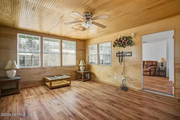 a living room with furniture floor to ceiling window and wooden floor
