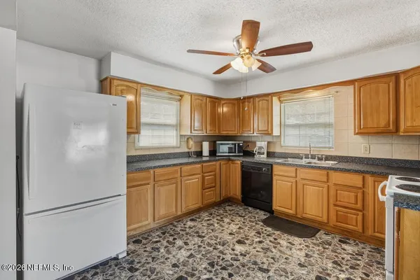 a kitchen with stainless steel appliances granite countertop a refrigerator a sink a stove a dining table and chairs