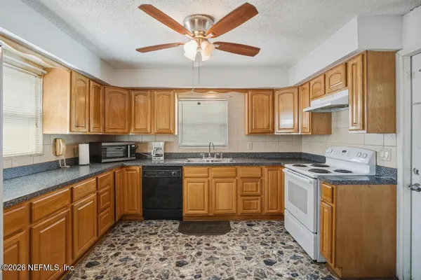 a kitchen with stainless steel appliances granite countertop a sink a stove a refrigerator cabinets and a window