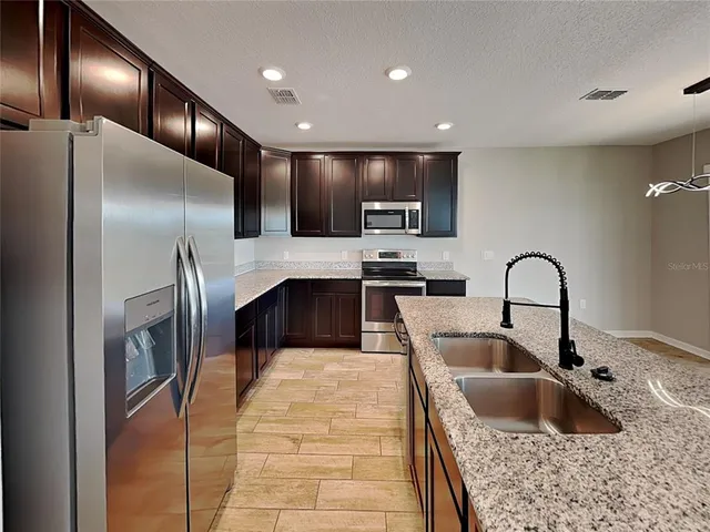 a kitchen with stainless steel appliances granite countertop a sink and a refrigerator
