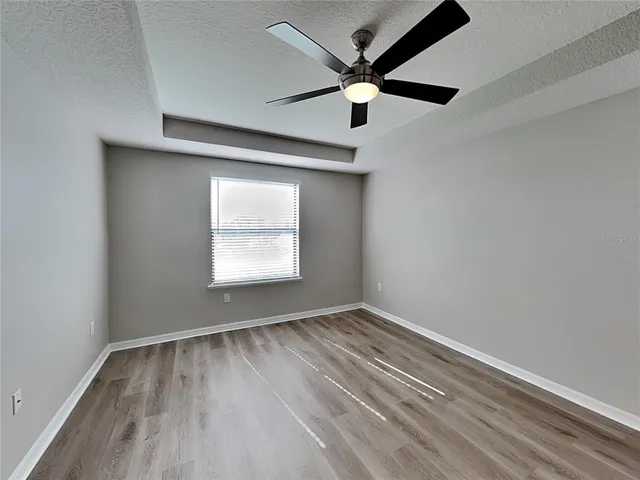 an empty room with a window and a ceiling fan