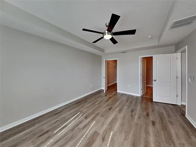 a view of empty room with wooden floor and ceiling fan