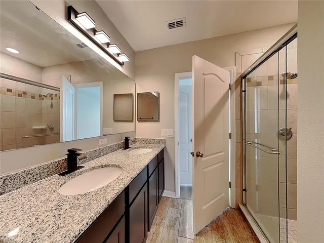 a bathroom with a granite countertop sink a mirror and shower
