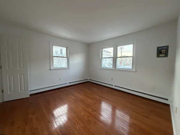 an empty room with wooden floor and windows